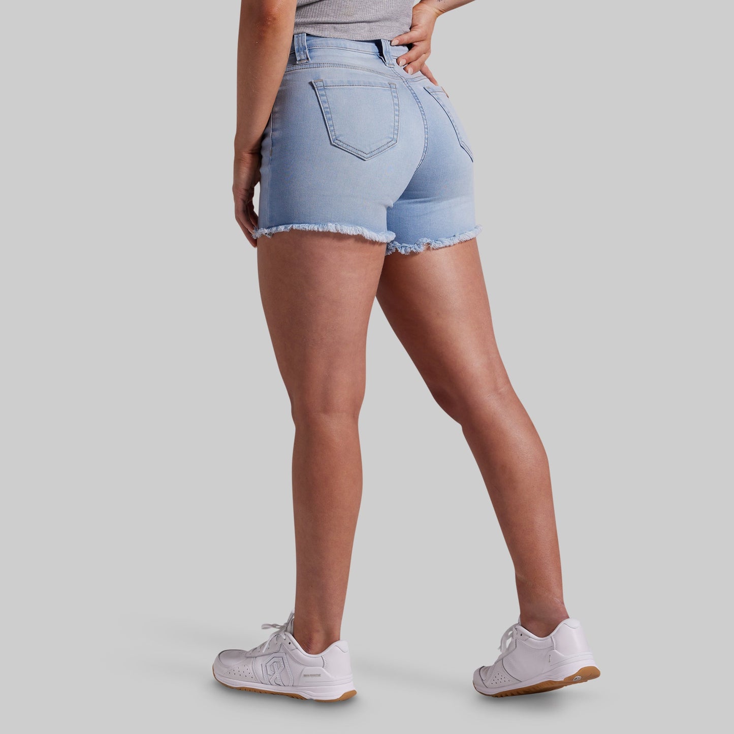 Person wearing light blue denim shorts on a gray background