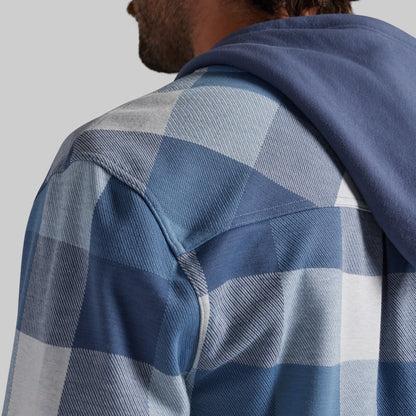 Close-up of a man wearing a blue and white buffalo plaid hooded flannel shirt, showing the texture of the fabric and the hood.