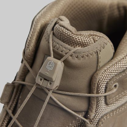 Close-up of a tan tactical boot with a brand logo on a gray background