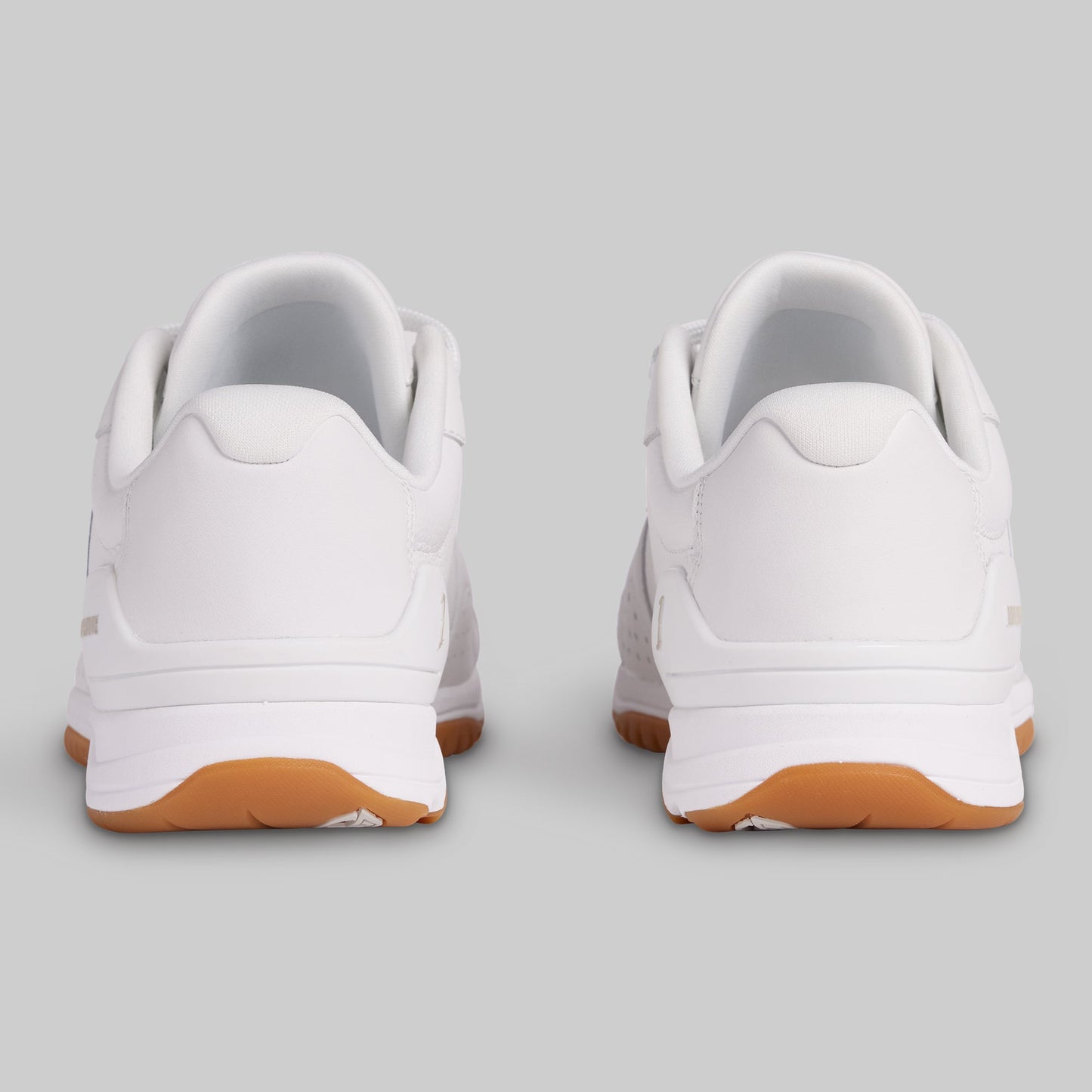 White sneakers with brown soles on a light gray background