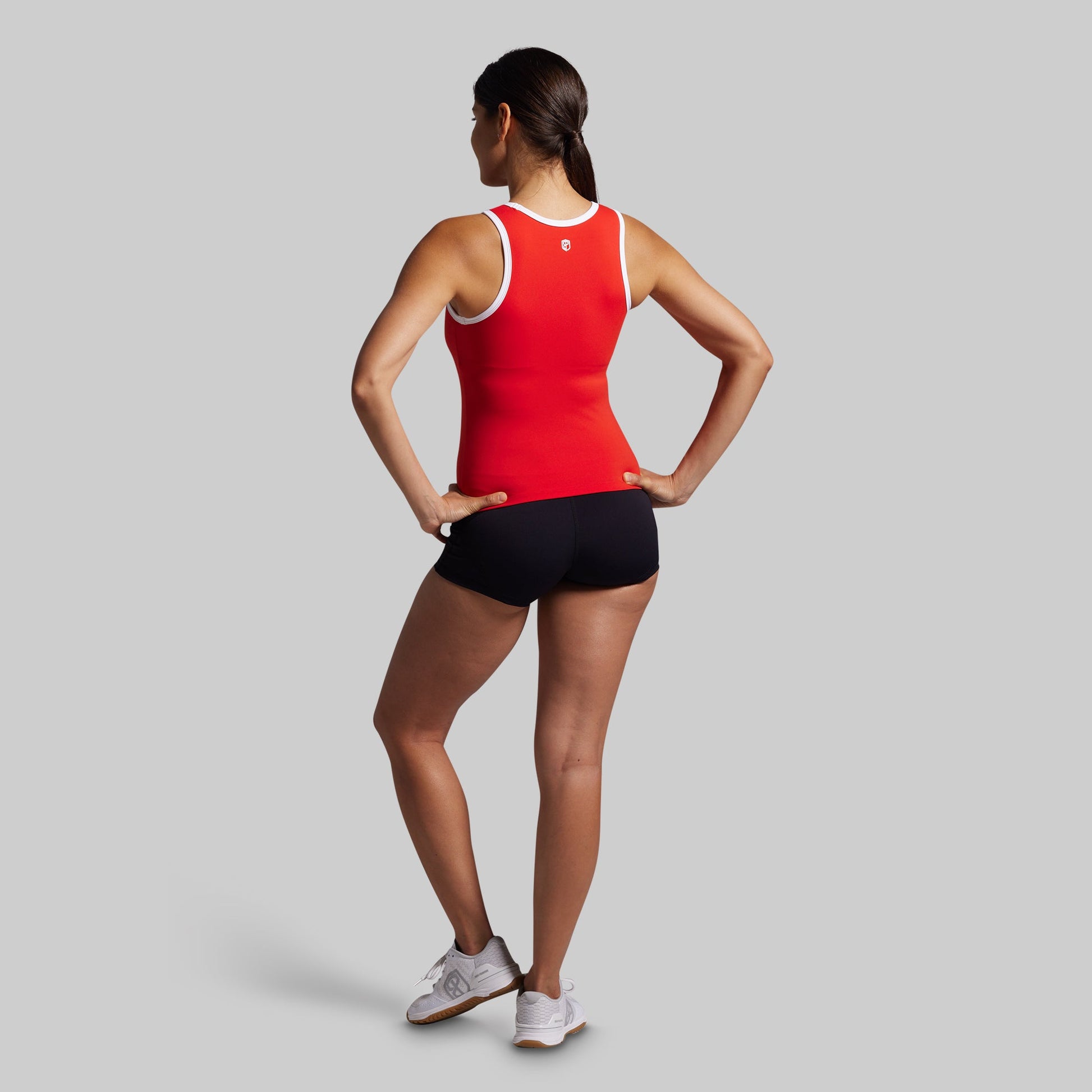 Person wearing a red tank top and black shorts on a gray background