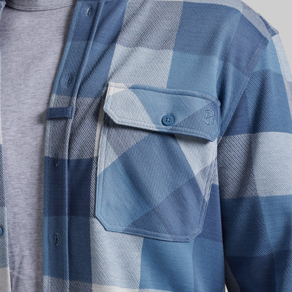 Close-up of a blue and white plaid button-up shirt worn over a heather gray t-shirt, featuring a chest pocket with a button flap.