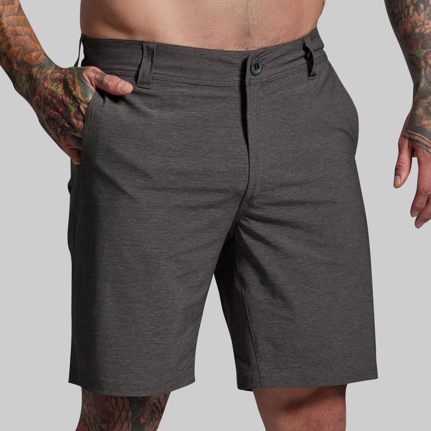 Person wearing dark gray shorts on a plain background