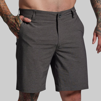Person wearing dark gray shorts on a plain background