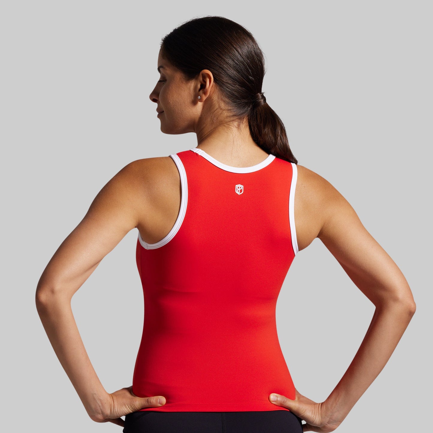 Woman wearing a red tank top with a logo on a gray background
