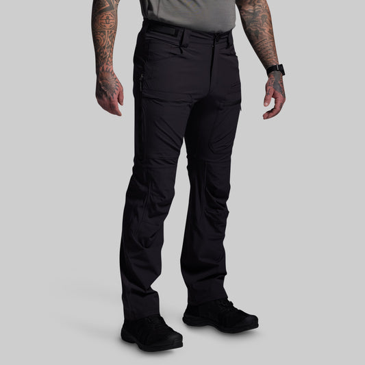 Person wearing black outdoor pants on a gray background