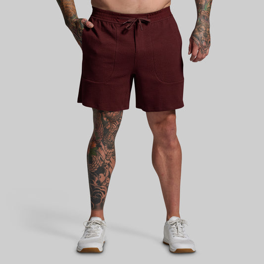 Person wearing maroon shorts on a gray background