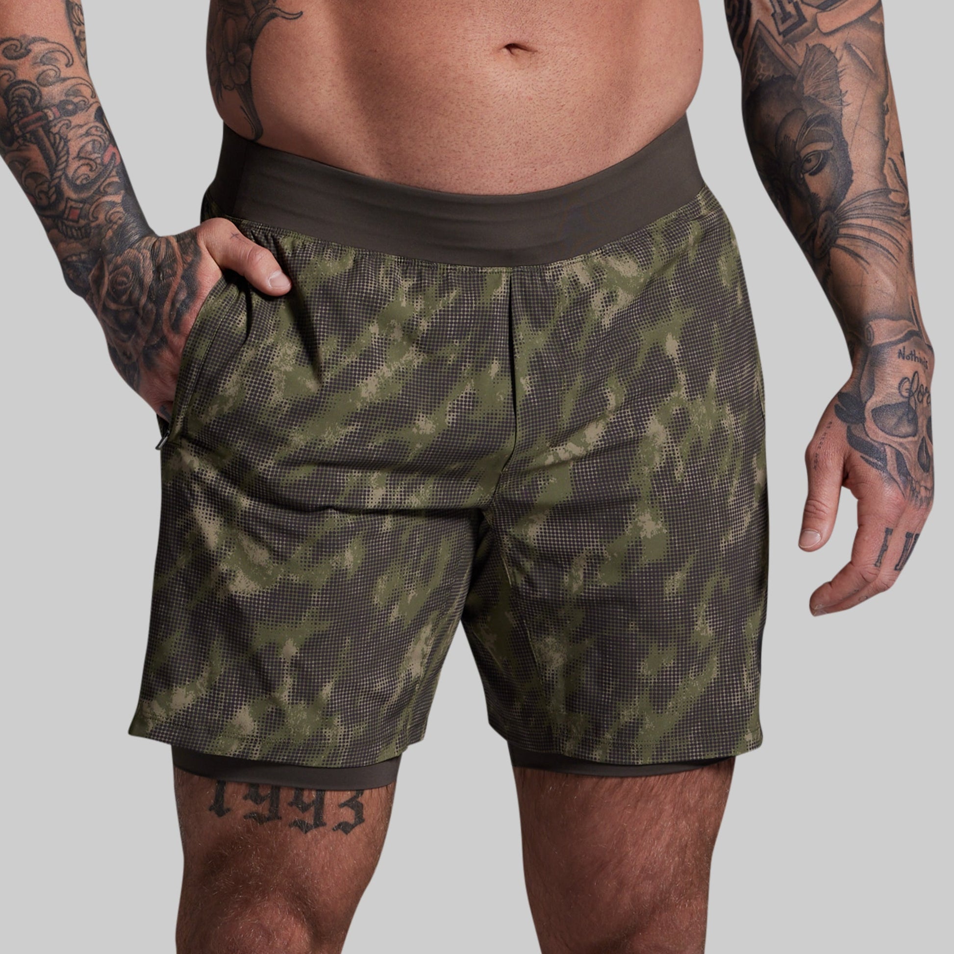 Person wearing green camouflage shorts on a gray background