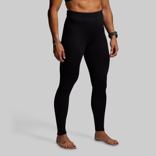 Person wearing black base layer leggings on a gray background