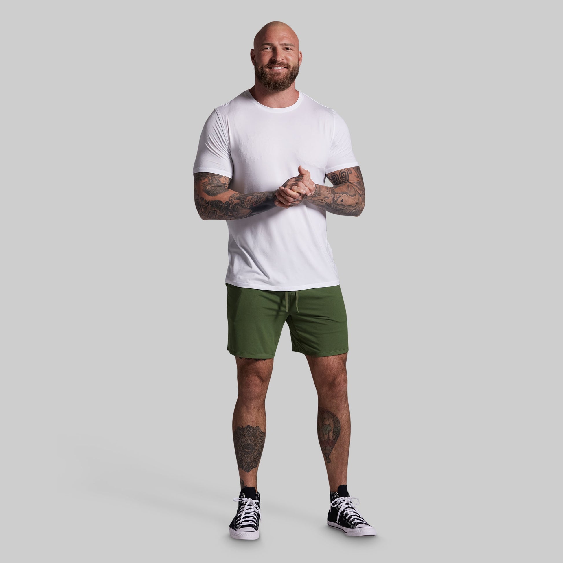 Man wearing a white t-shirt and green shorts on a gray background