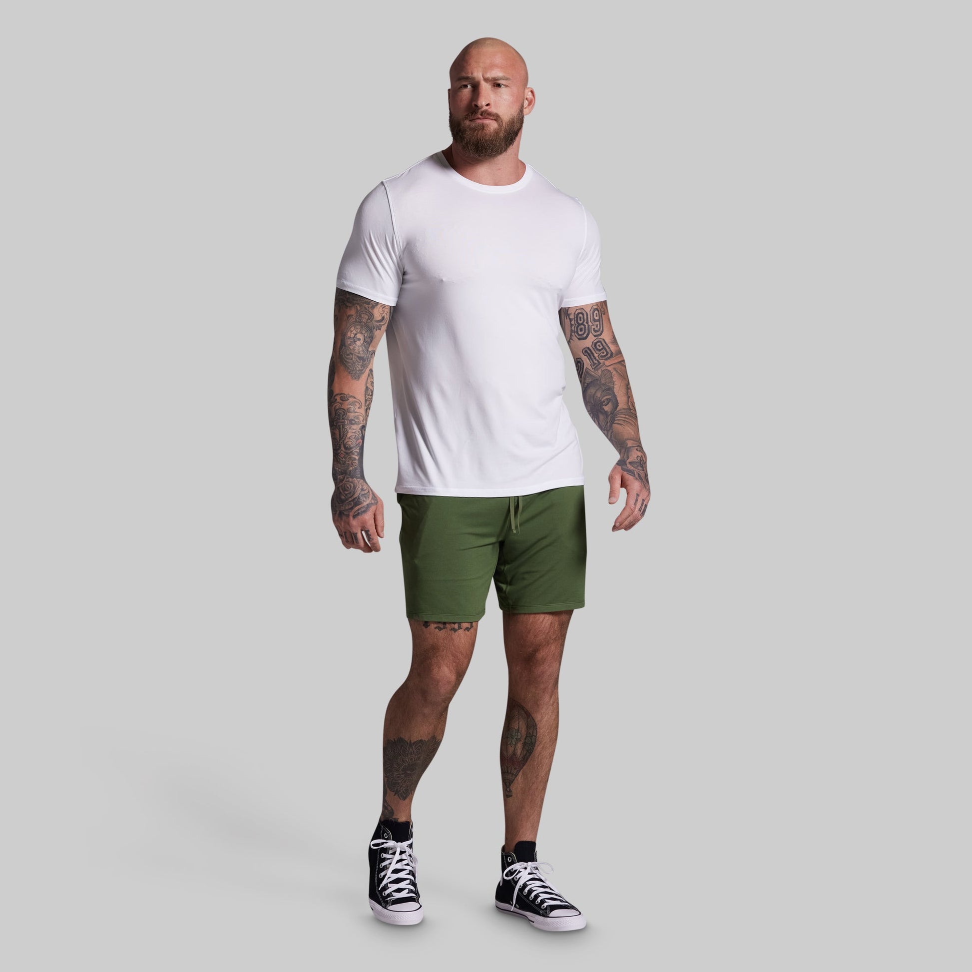 Man wearing a white t-shirt and green shorts on a gray background