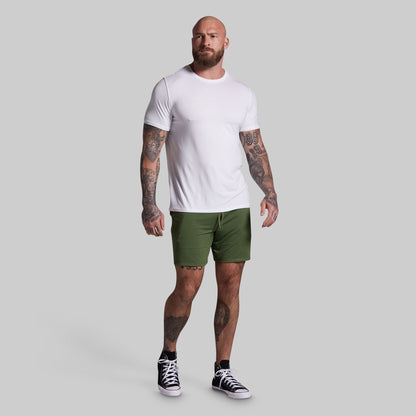 Man wearing a white t-shirt and green shorts on a gray background