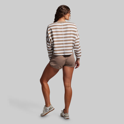 Person wearing a striped sweater and shorts on a plain background