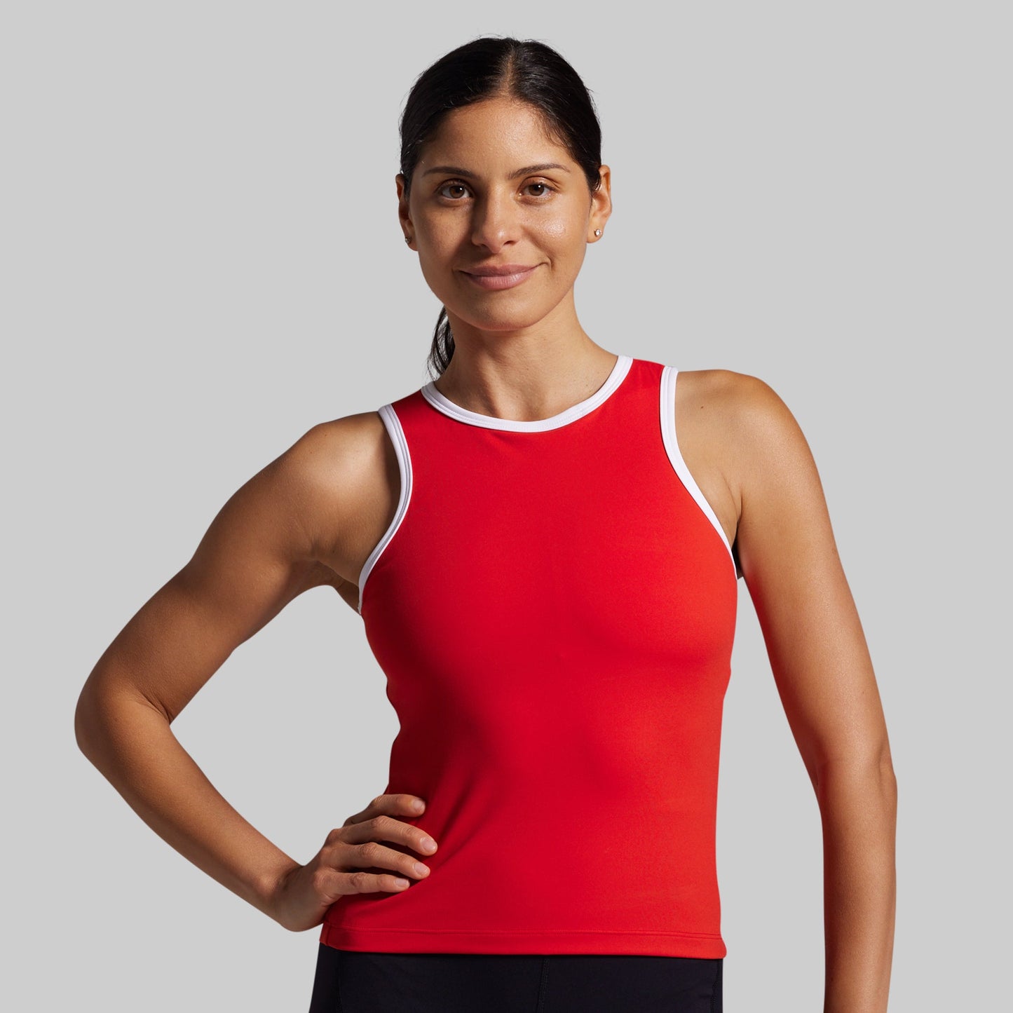 Woman wearing a red tank top with white trim on a gray background