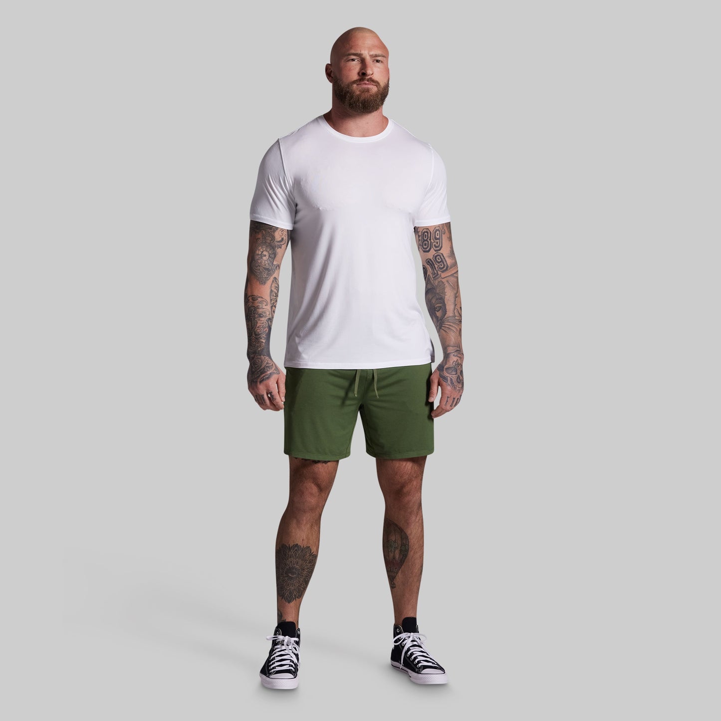 Man wearing a white t-shirt and green shorts on a gray background