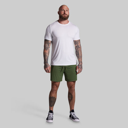 Man wearing a white t-shirt and green shorts on a gray background