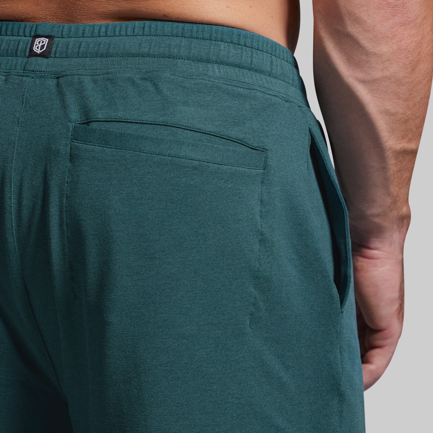 Teal pants with a visible brand logo on a neutral background