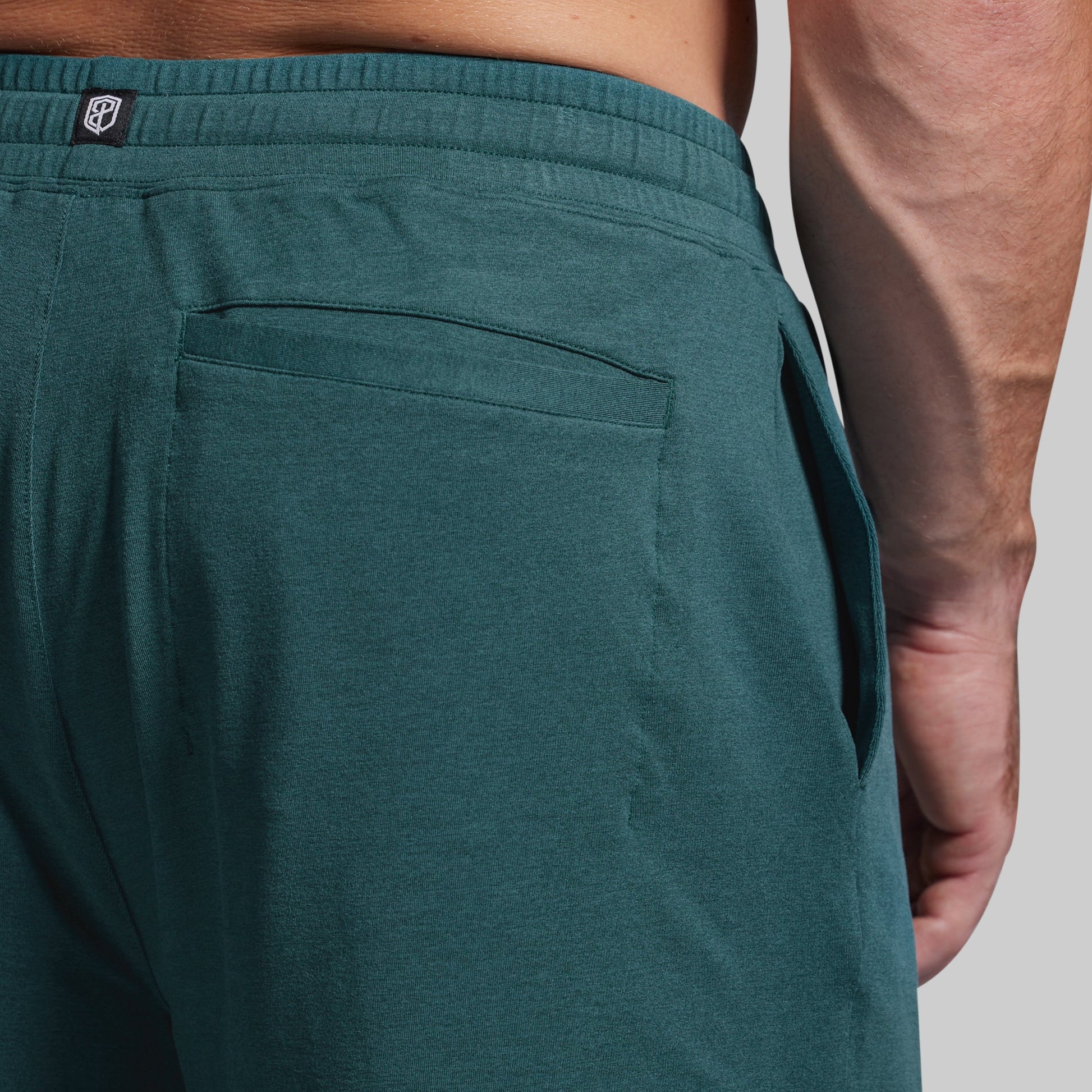 Teal pants with a visible brand logo on a neutral background