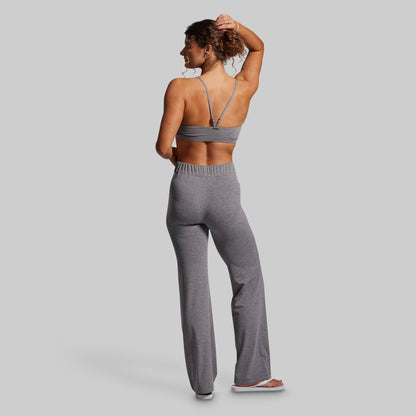 Woman wearing a gray sports bra and leggings on a light gray background