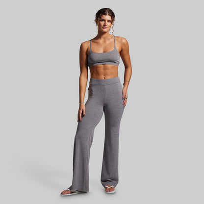 Woman wearing a gray sports bra and wide-leg pants on a light gray background