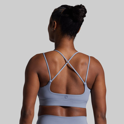 Person wearing a light blue sports bra and leggings on a gray background