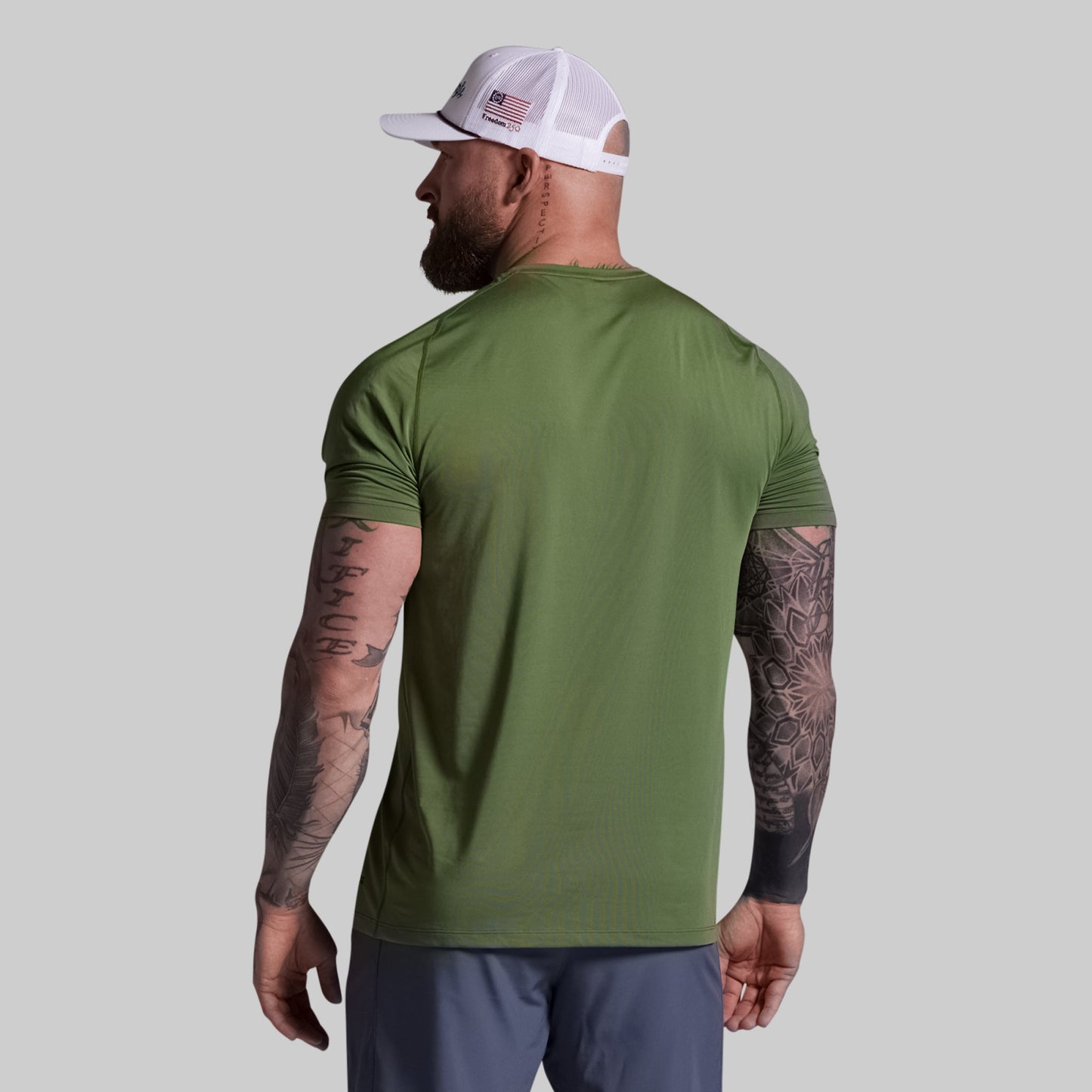 Man wearing a green t-shirt and white cap on a gray background