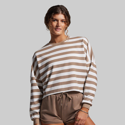 Woman wearing a brown and white striped sweater with matching pants on a gray background