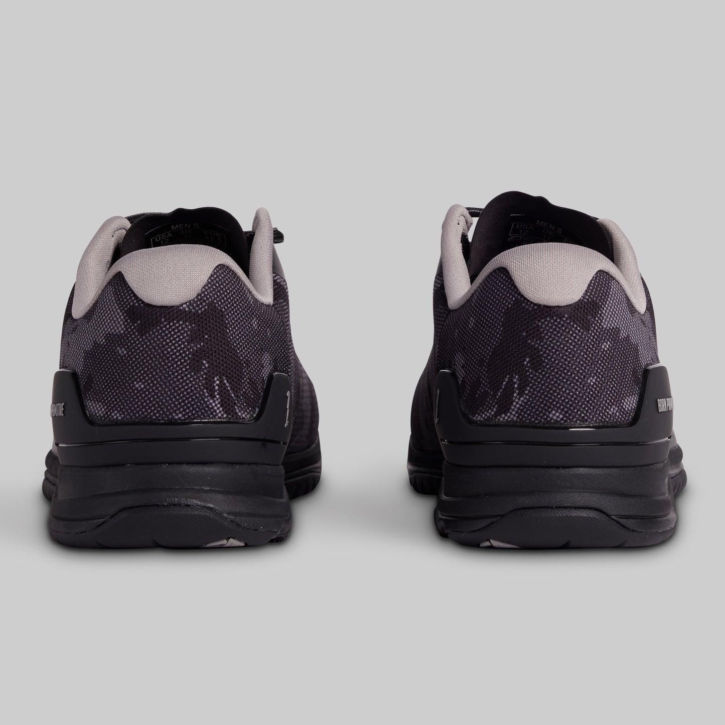 Black and grey camouflage athletic shoes on a gray background