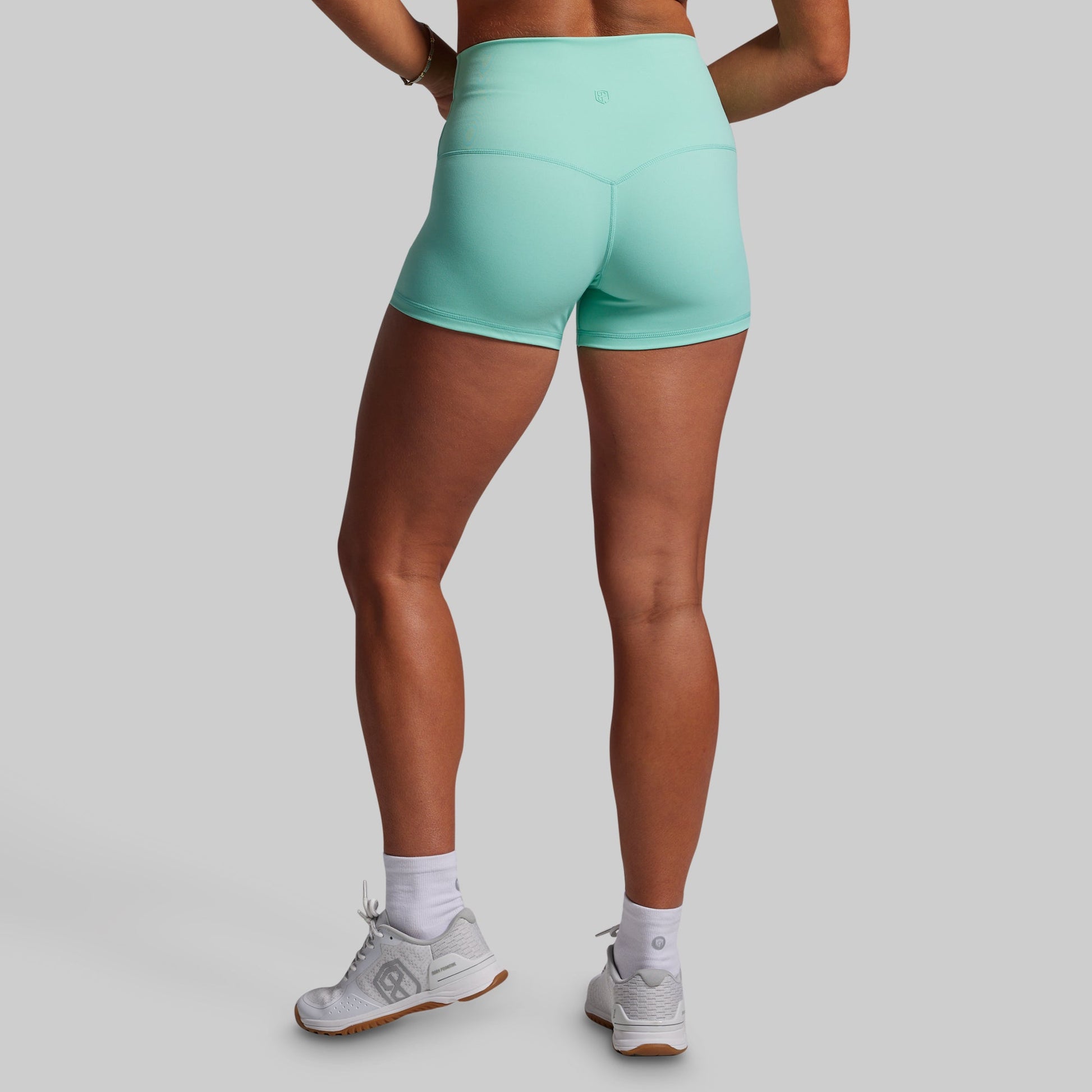 Person wearing teal athletic shorts on a gray background