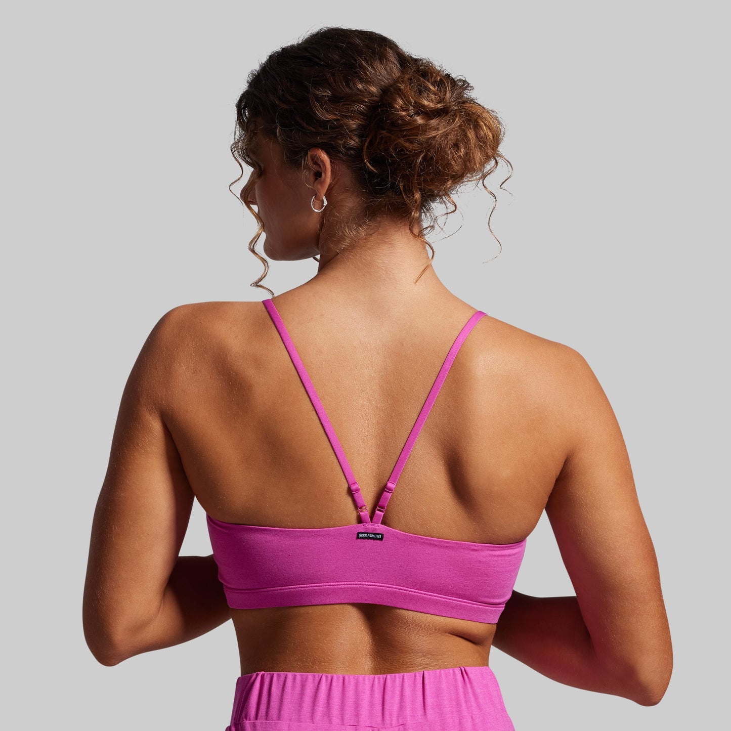 Woman wearing a pink sports bra and shorts on a gray background