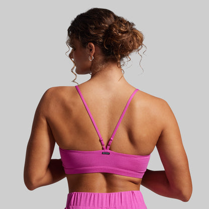 Woman wearing a pink sports bra and shorts on a gray background
