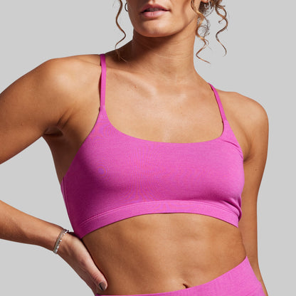 Woman wearing a pink sports bra and leggings against a gray background