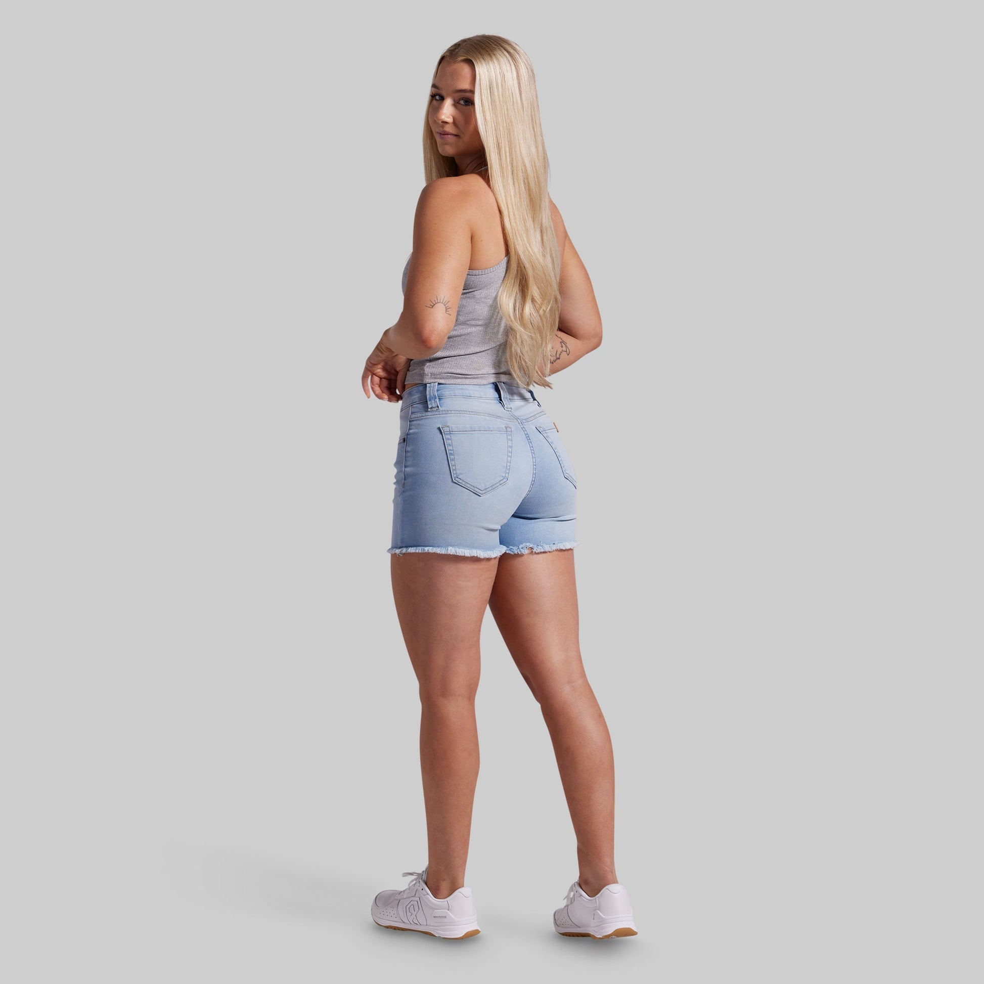 Woman wearing light blue denim shorts on a gray background