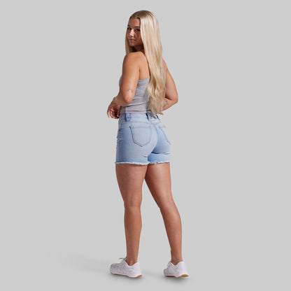 Woman wearing light blue denim shorts on a gray background