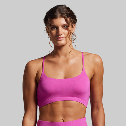 Woman wearing a pink sports bra and leggings against a gray background