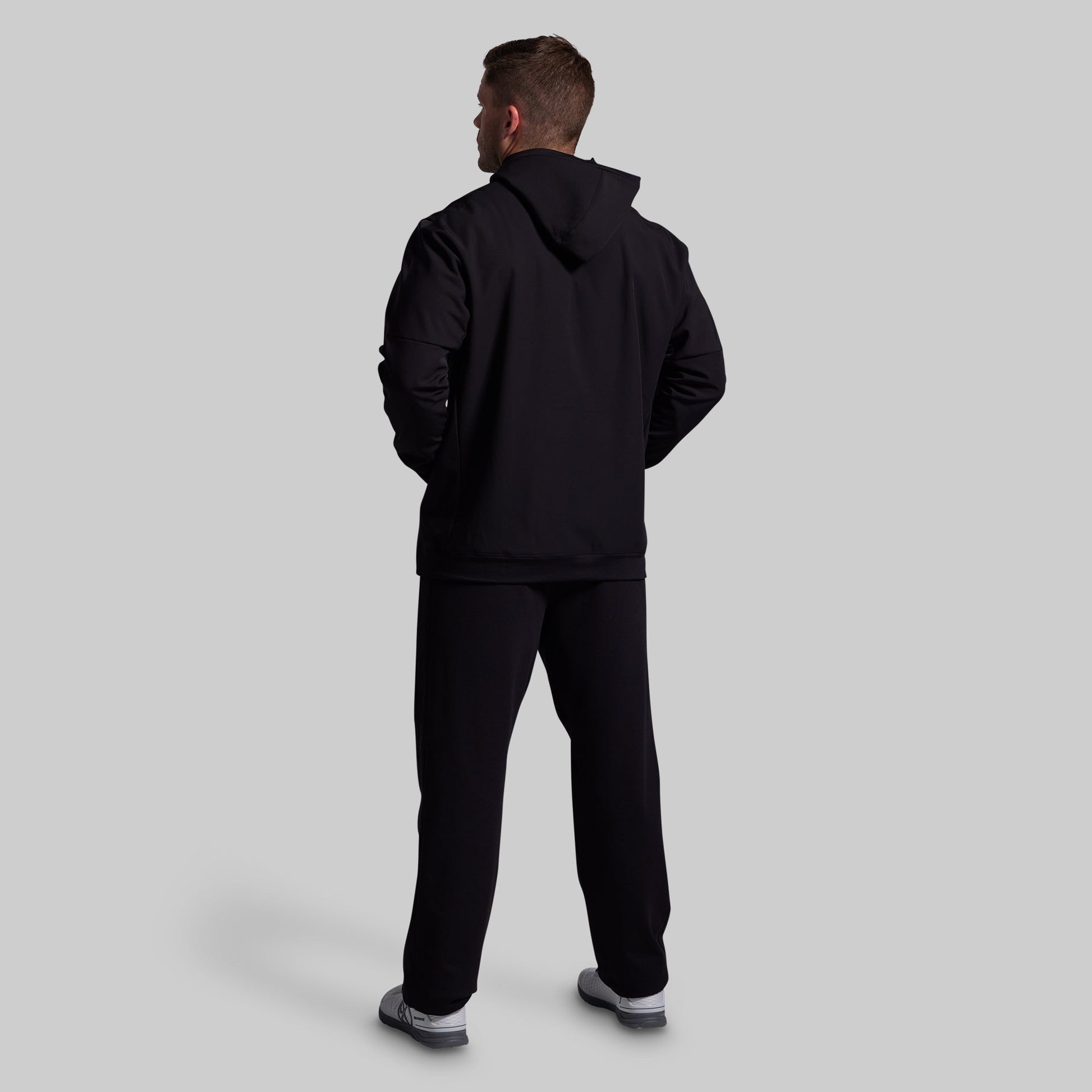 Person wearing a black tracksuit on a light gray background