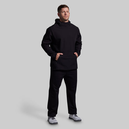 Man wearing a black hoodie and pants on a light gray background