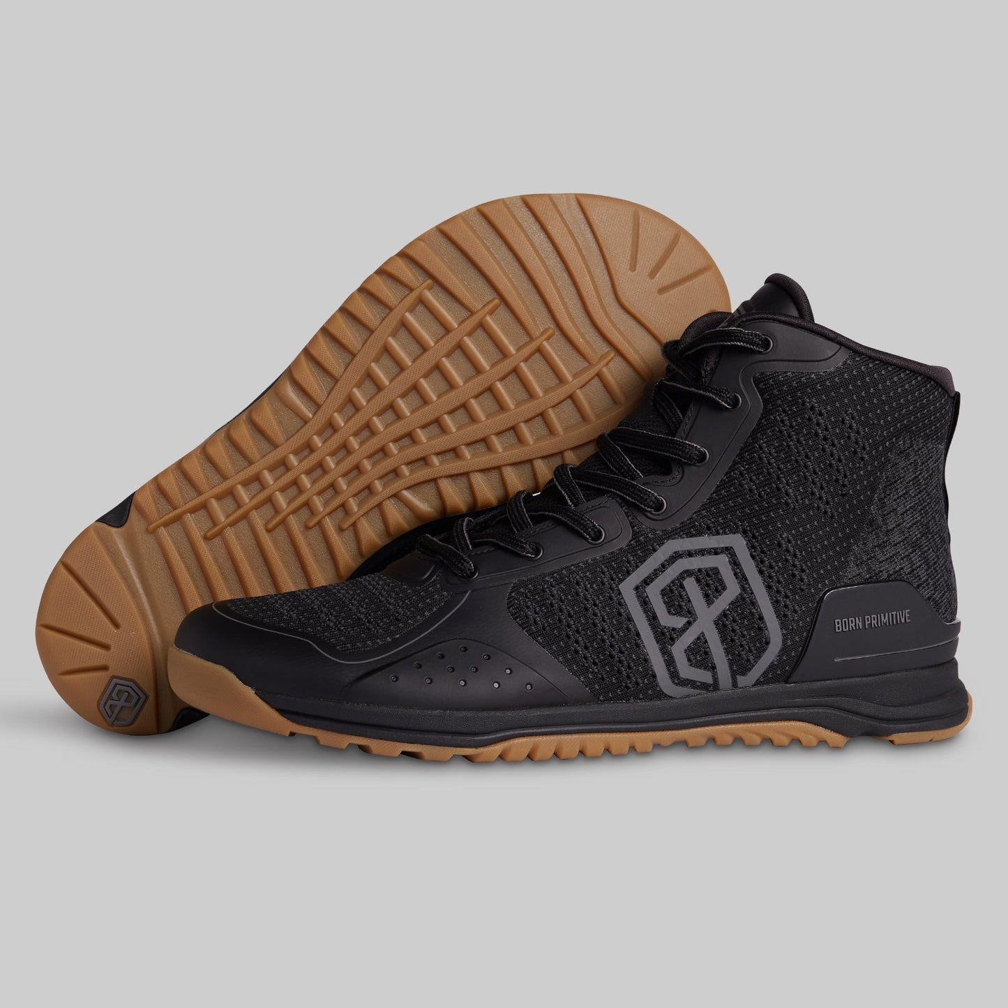 Black athletic shoe with brown sole on a gray background