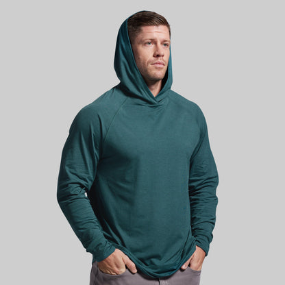 Man wearing a teal hoodie against a gray background