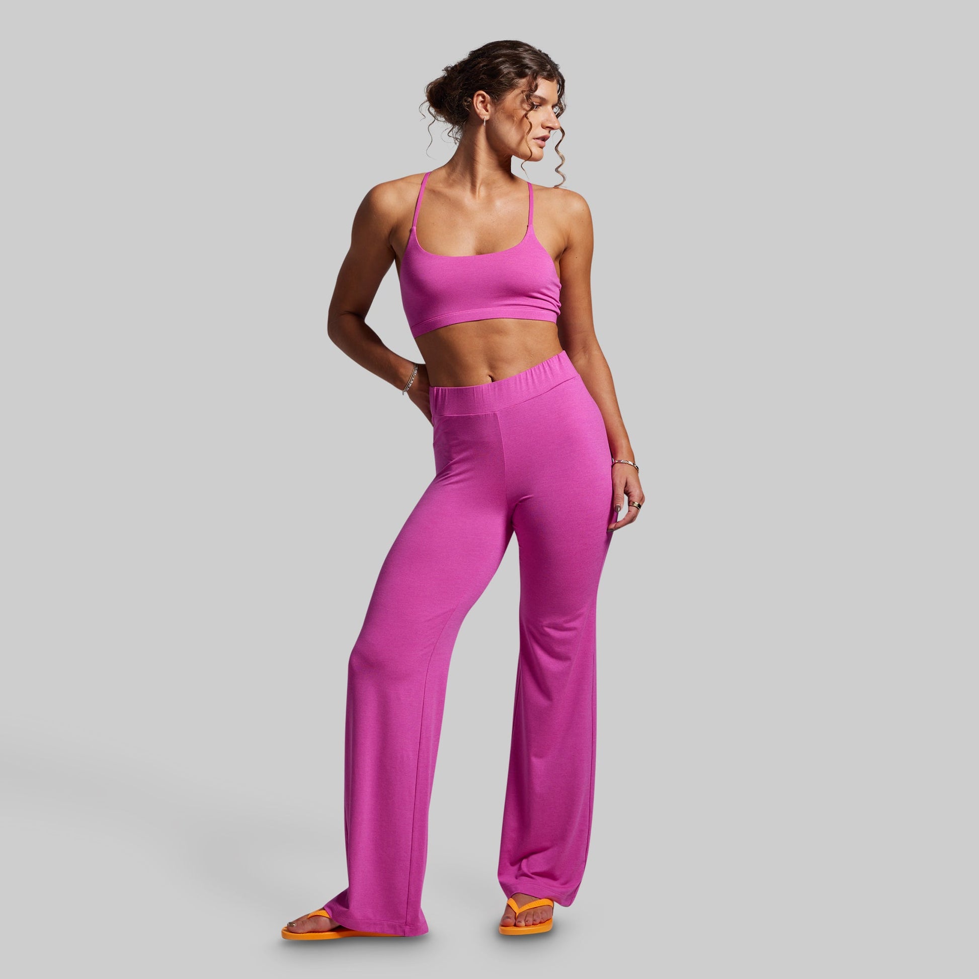 Woman wearing a pink sports bra and leggings on a gray background