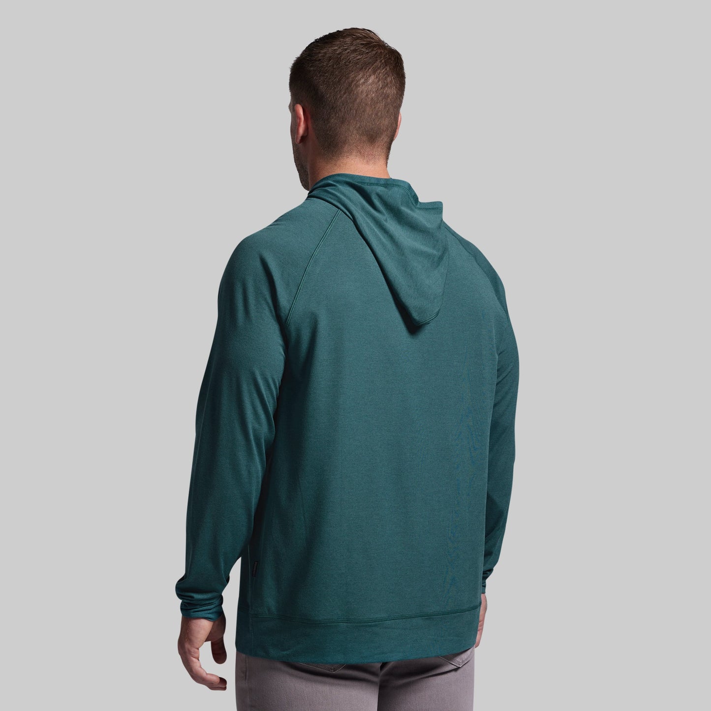 Man wearing a teal hoodie from behind on a gray background