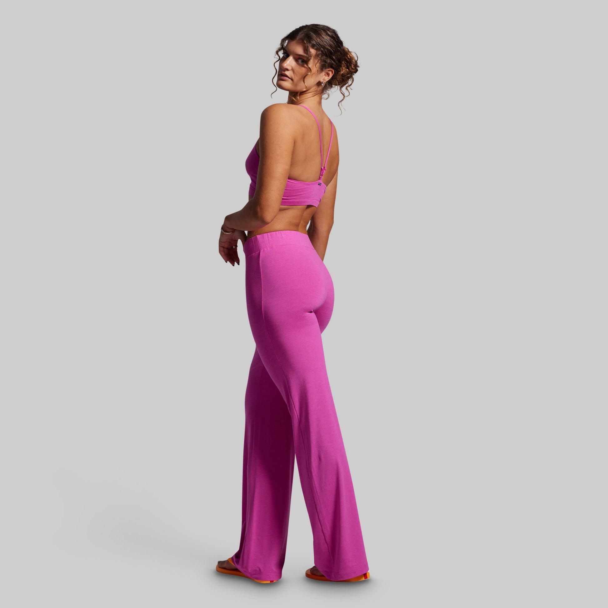 Woman wearing a bright pink outfit on a gray background