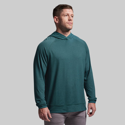 Man wearing a teal hoodie against a gray background