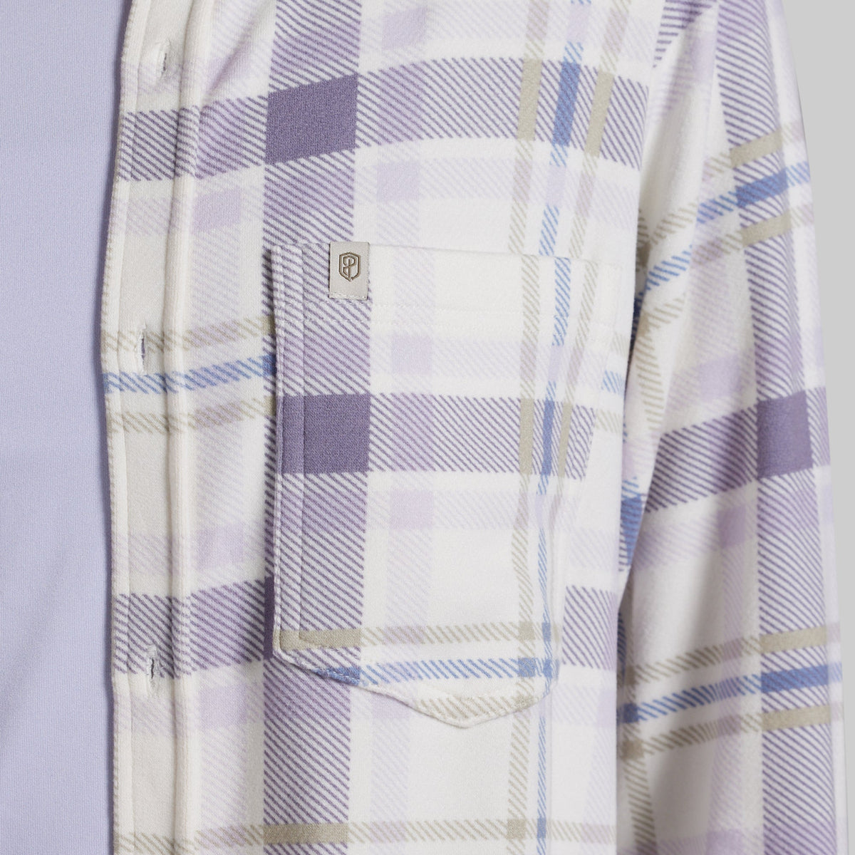 Close-up of a plaid button-up shirt with a chest pocket, featuring a white base with lavender, light blue, and beige stripes.