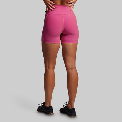 Person wearing pink ribbed athletic shorts on a gray background