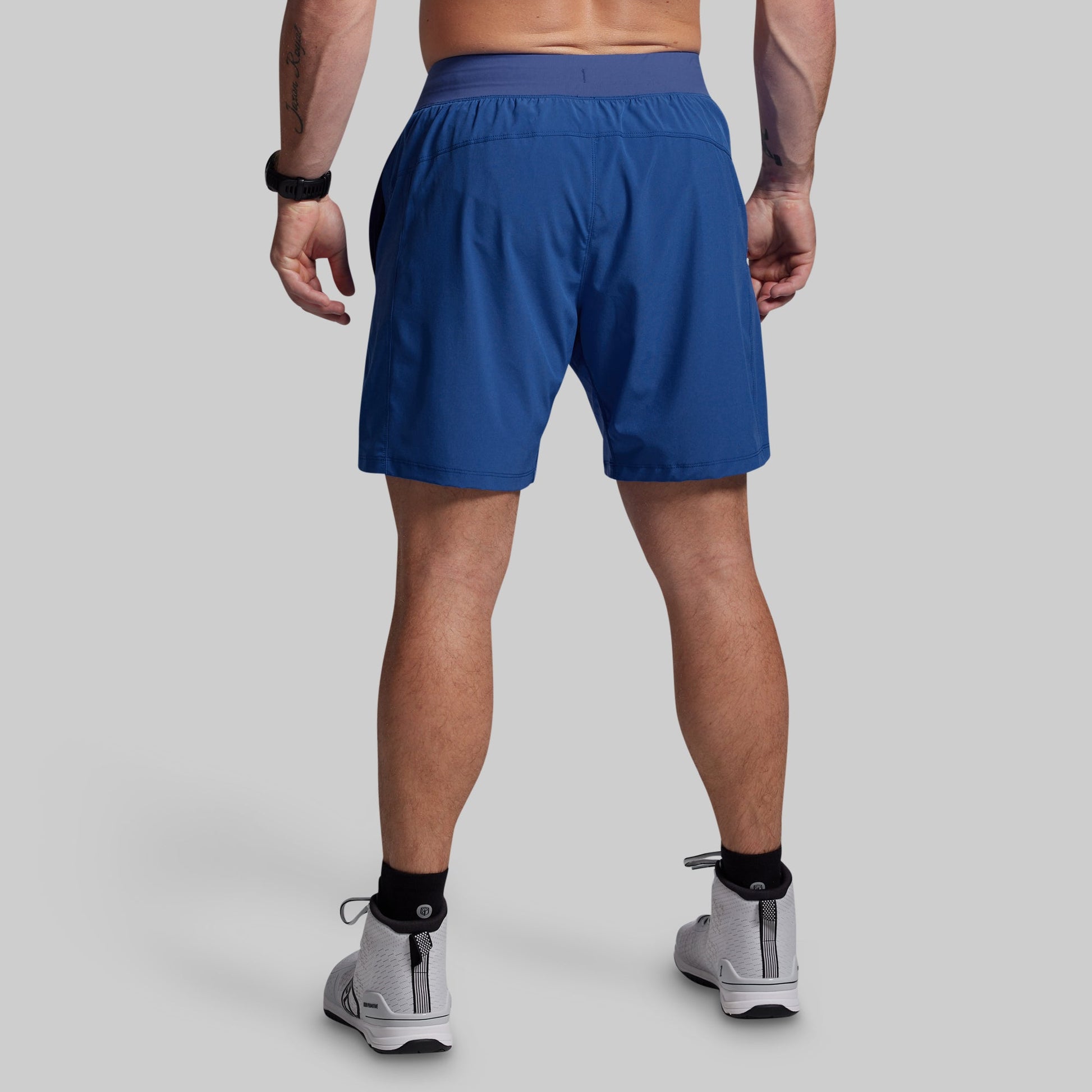 Person wearing blue athletic shorts on a gray background