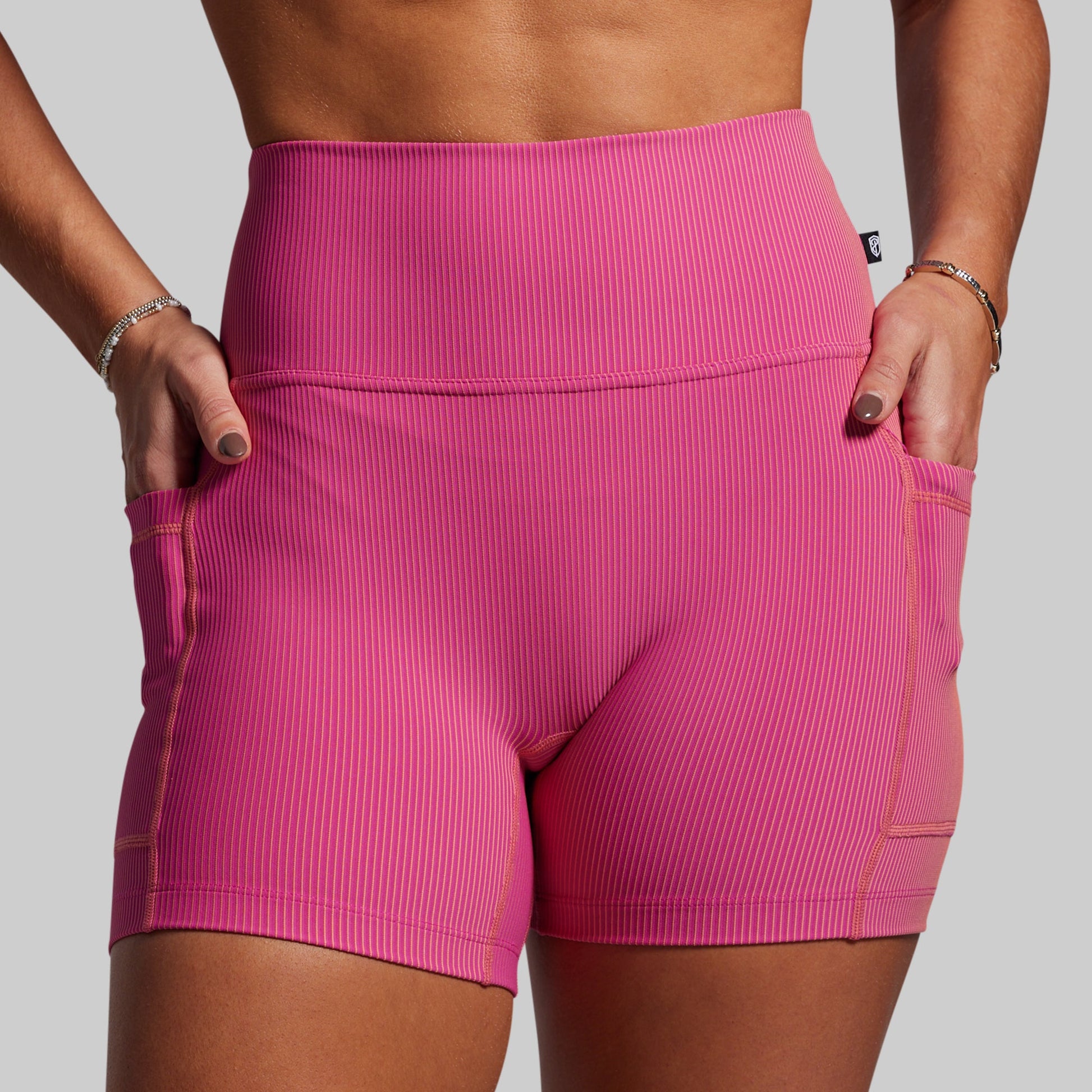 Women wearing pink ribbed athletic shorts on a gray background