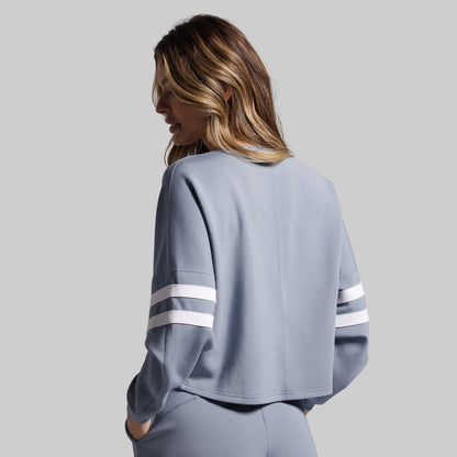 Woman wearing a gray sweatshirt with white stripes on a plain background