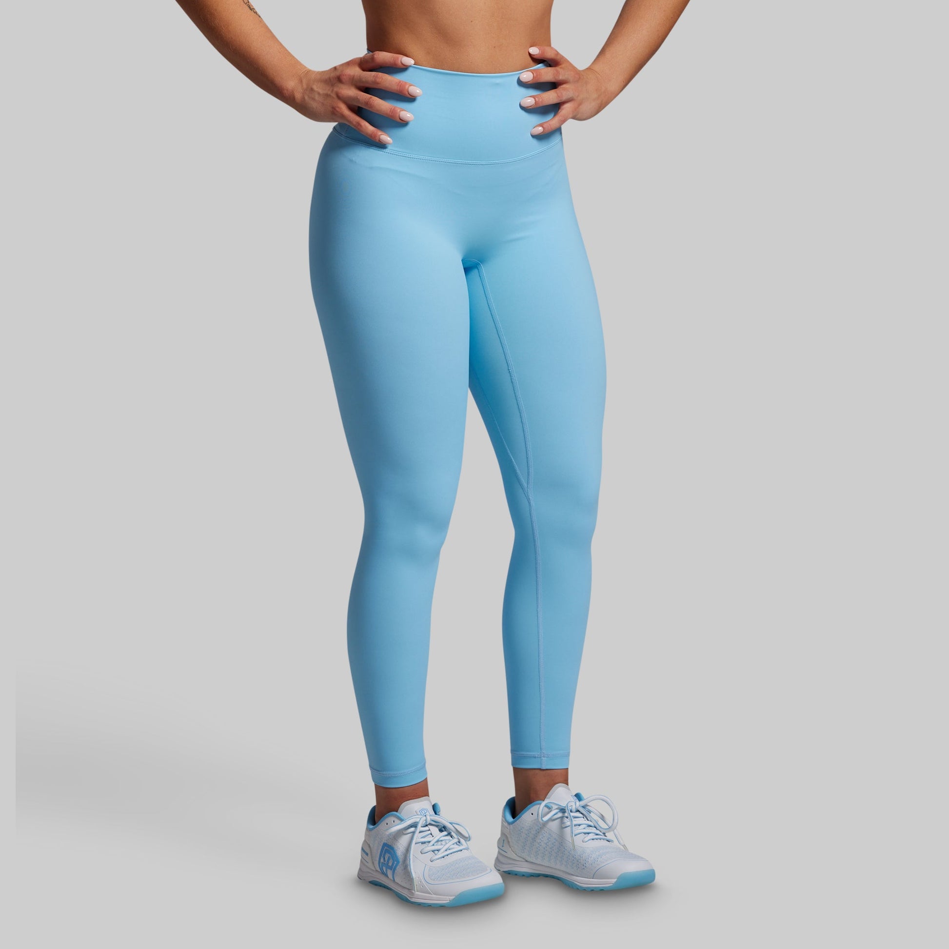 Person wearing light blue leggings on a gray background