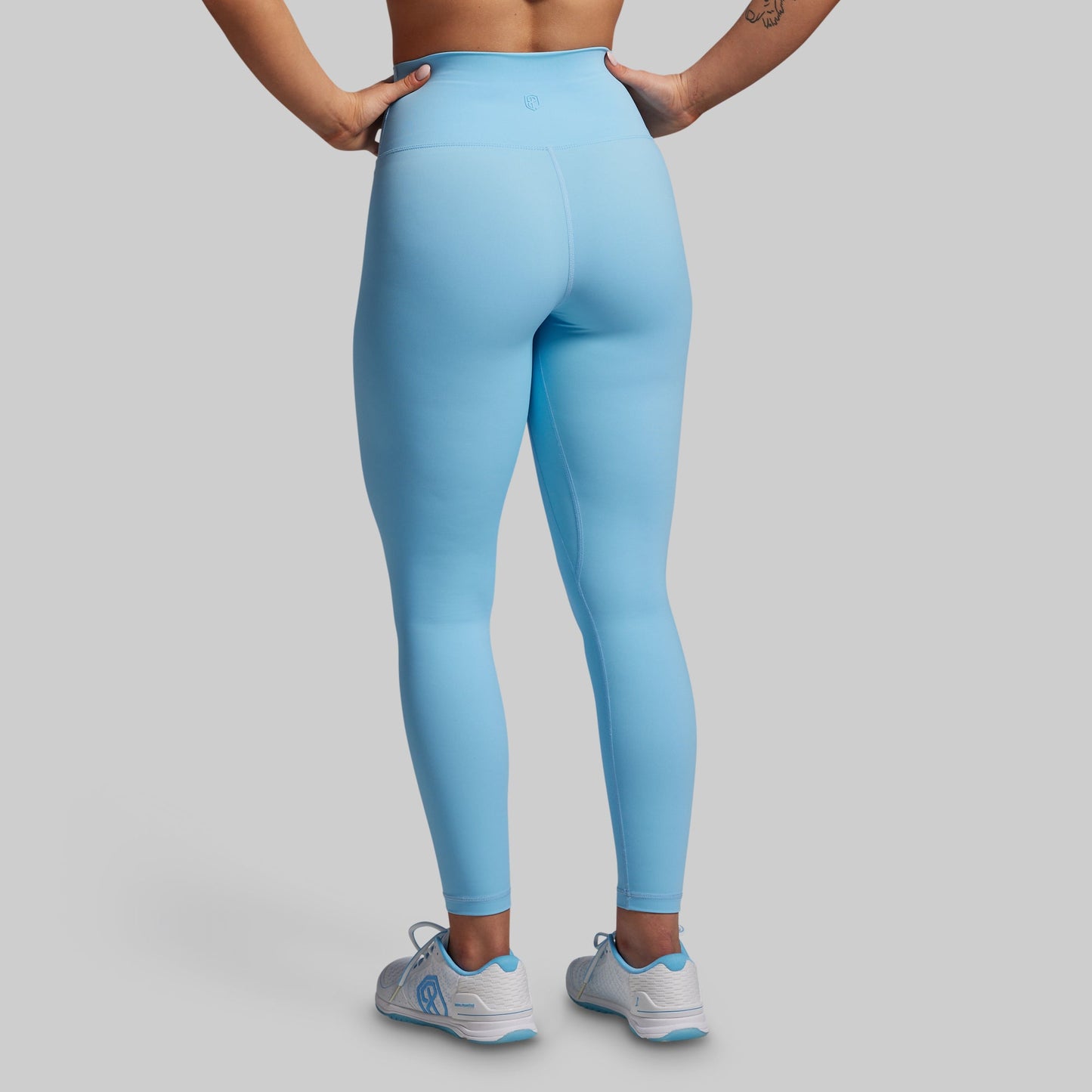 Person wearing light blue leggings on a gray background